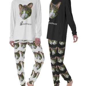 May include: A white and black long-sleeved pajama set with a cat face print on the top and a repeating cat face print on the pants. The text "Catress" is printed on the top.