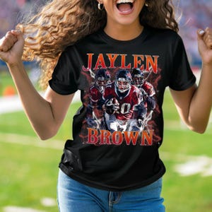 Puede incluir: Camiseta negra con un gr&aacute;fico de un jugador de f&uacute;tbol americano con un uniforme rojo y blanco. El texto "JAYLEN BROWN" est&aacute; impreso en la camiseta.
