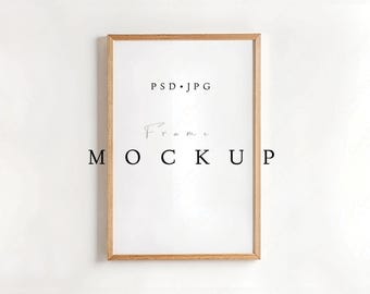 May include: A rectangular wooden frame with a white interior. The frame has a light brown color. The text "PSD.JPG" is at the top, and "Frame MOCKUP" is written in black letters in the center of the frame.