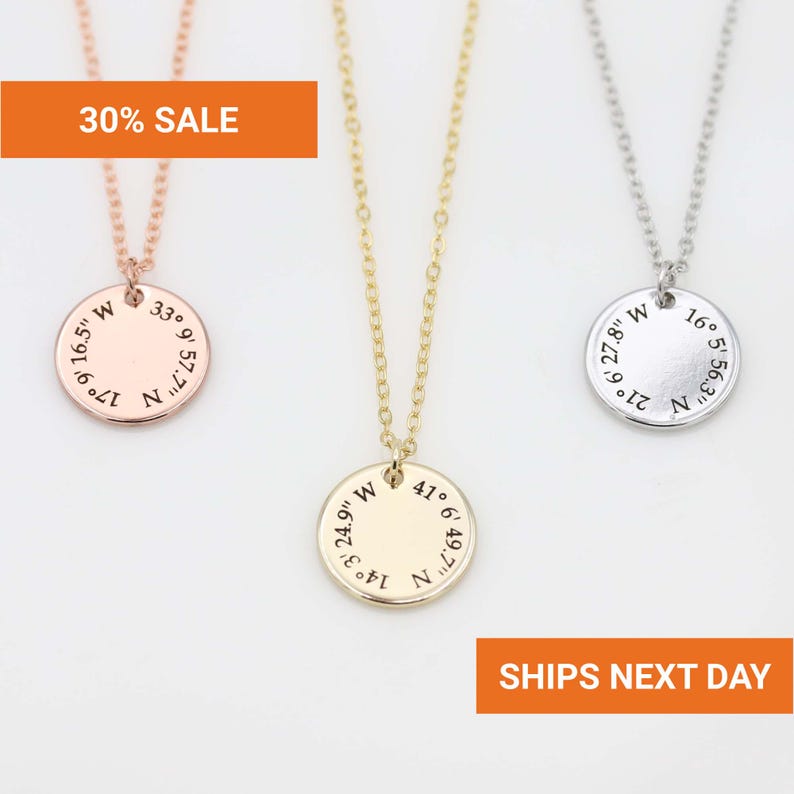 Puede incluir: Tres collares con colgantes en oro rosa, oro y plata. Cada collar presenta un colgante circular grabado con coordenadas. El colgante de oro rosa tiene el texto "30% SALE". El colgante plateado tiene el texto "SHIPS NEXT DAY".