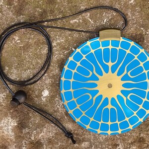 May include: A gold and blue pendant necklace with a geometric design. The pendant is round and has a gold center with a blue pattern.