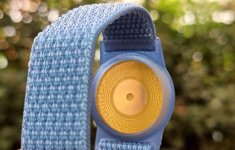 May include: A blue and white patterned wristband with a yellow circular sensor in the centre.