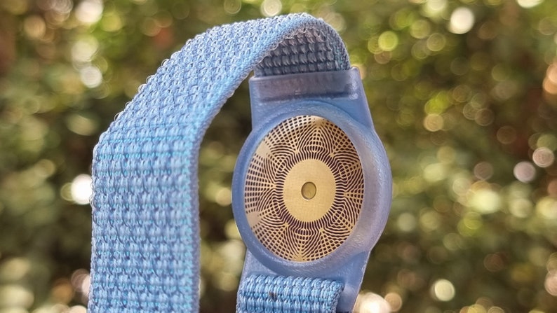 May include: A blue and white patterned wristband with a gold-coloured sensor on the back.