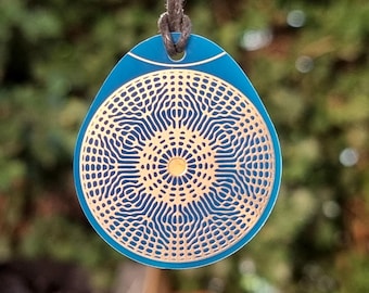 May include: A blue and gold pendant with a geometric pattern. The pendant is shaped like a teardrop and has a cord attached to it.