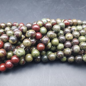 May include: A strand of green, red and brown speckled round beads. The beads are made of natural stone and are perfect for jewellery making.