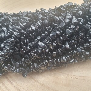 Peut inclure: Un brin de perles en obsidienne noire. Les perles sont de forme irrégulière et ont une finition brillante.