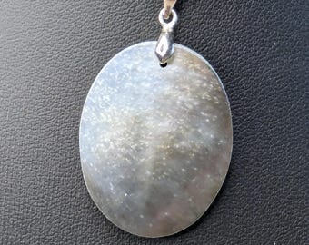 May include: A black oval pendant with a silver bail, hanging from a black cord necklace. The pendant has a pearlescent sheen and a textured surface.