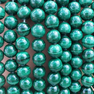 Peut inclure: Un brin de perles rondes en malachite verte. Les perles ont une finition lisse et polie et un motif tourbillonnant.