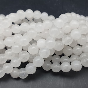 Peut inclure: Un brin de perles rondes blanches en jade blanc naturel. Les perles sont lisses et polies, avec une apparence légèrement translucide.