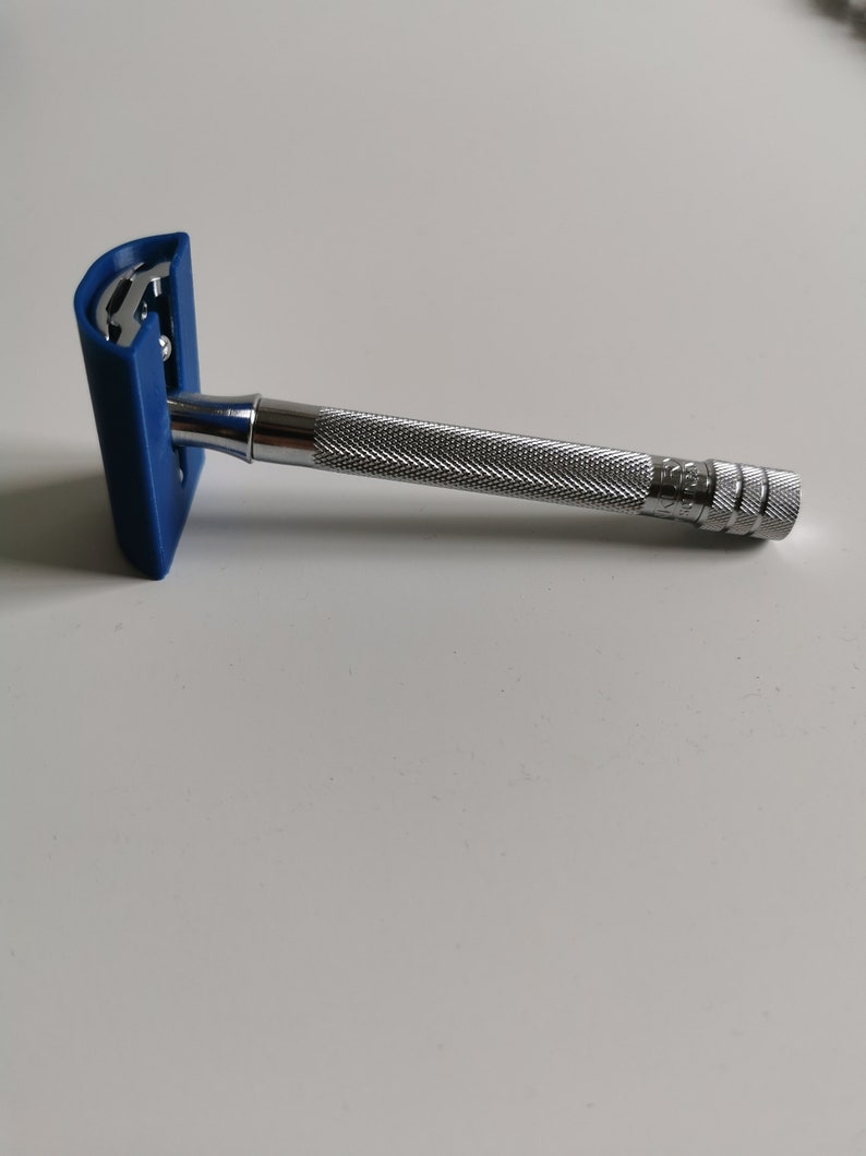 May include: A silver safety razor with a blue plastic handle. The razor has a textured grip and a safety bar.
