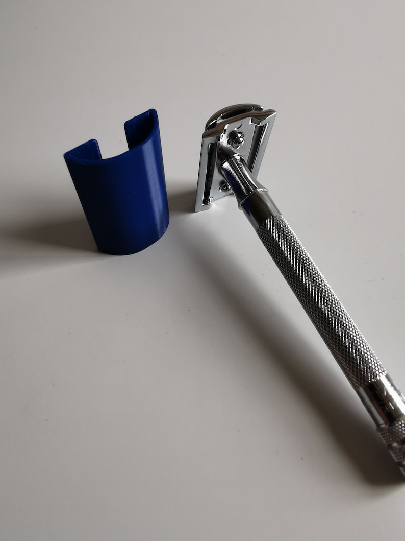 May include: A silver safety razor with a blue plastic stand. The razor has a textured handle and a chrome head.