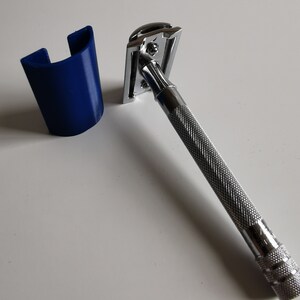 May include: A silver safety razor with a blue plastic stand. The razor has a chrome finish and a textured handle.