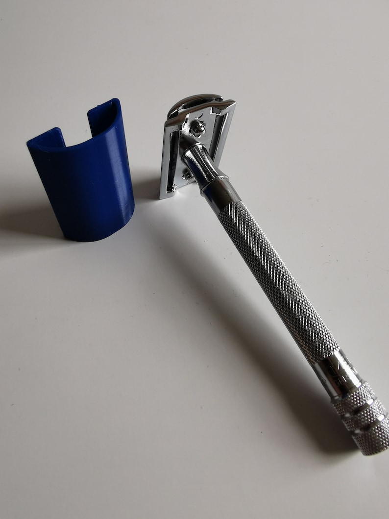 May include: A silver safety razor with a blue plastic stand. The razor has a chrome finish and a textured handle.