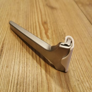 May include: A silver razor with a white plastic handle. The razor is designed for men's shaving.