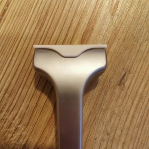 May include: A silver razor with a white plastic head. The razor is designed for shaving.