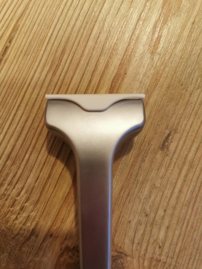 May include: A silver razor with a white plastic head. The razor is designed for shaving.
