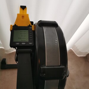 May include: Black and yellow rowing machine with a digital display showing the time, distance, strokes per minute, and calories burned. The display also shows the words "Units", "Display", and "Menu".