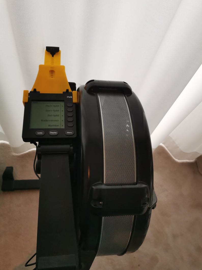 May include: Black and yellow rowing machine with a digital display showing the time, distance, strokes per minute, and calories burned. The display also shows the words "Units", "Display", and "Menu".
