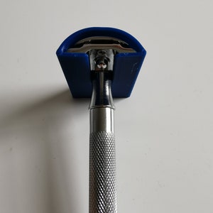 May include: A silver safety razor with a blue plastic cap. The razor has a textured handle.