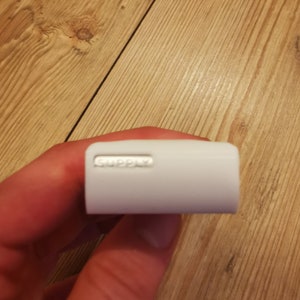 May include: White rectangular power adapter with the word "SUPPLY" printed on it.