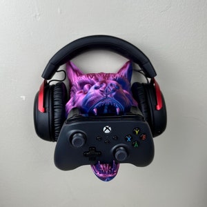 May include: A purple and blue wolf head wall mount with a black gaming headset and a black Xbox controller hanging from it.