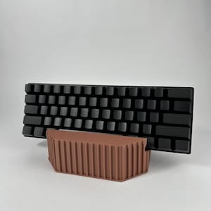 May include: A black keyboard with a brown stand. The stand has a ribbed design and is angled to elevate the keyboard.
