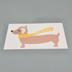 Puede incluir: Una tarjeta blanca con una ilustraci&oacute;n de dibujos animados de un dachshund marr&oacute;n que lleva un gorro de fiesta amarillo y una bufanda amarilla con la palabra "EINLADUNG" en ella.
