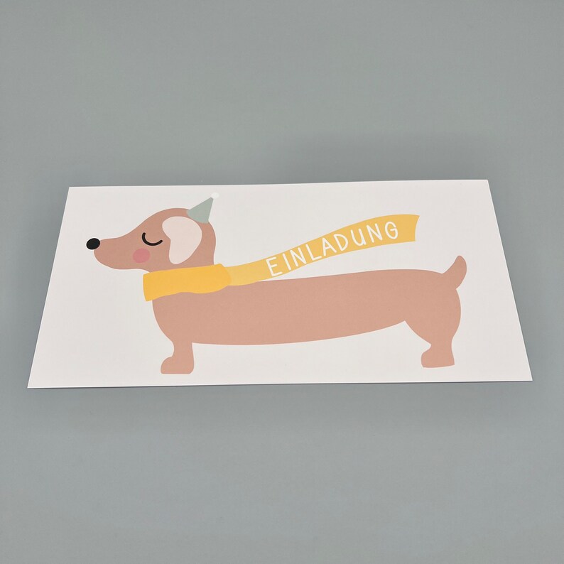 Puede incluir: Una tarjeta blanca con una ilustraci&oacute;n de dibujos animados de un dachshund marr&oacute;n que lleva un gorro de fiesta amarillo y una bufanda amarilla con la palabra "EINLADUNG" en ella.