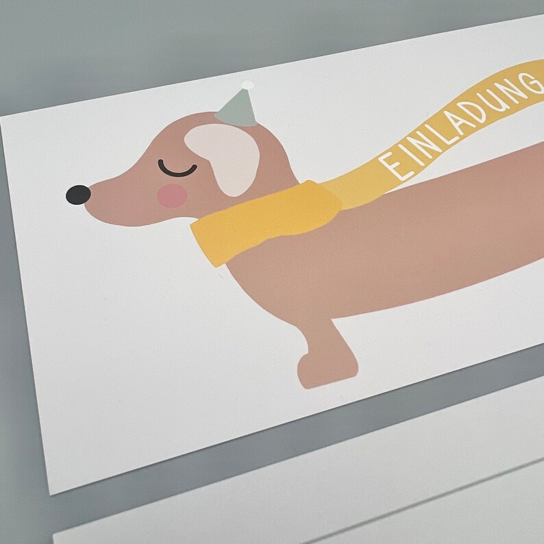 Puede incluir: Un dachshund marr&oacute;n y blanco con una bufanda amarilla y un gorro de fiesta con la palabra "EINLADUNG" escrita en la bufanda.