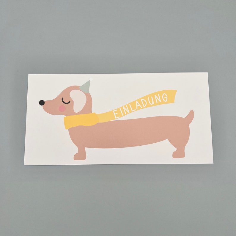 Puede incluir: Una tarjeta blanca con una ilustraci&oacute;n de dibujos animados de un dachshund marr&oacute;n que lleva una bufanda amarilla y un gorro de fiesta. La bufanda tiene la palabra "EINLADUNG" escrita en ella.