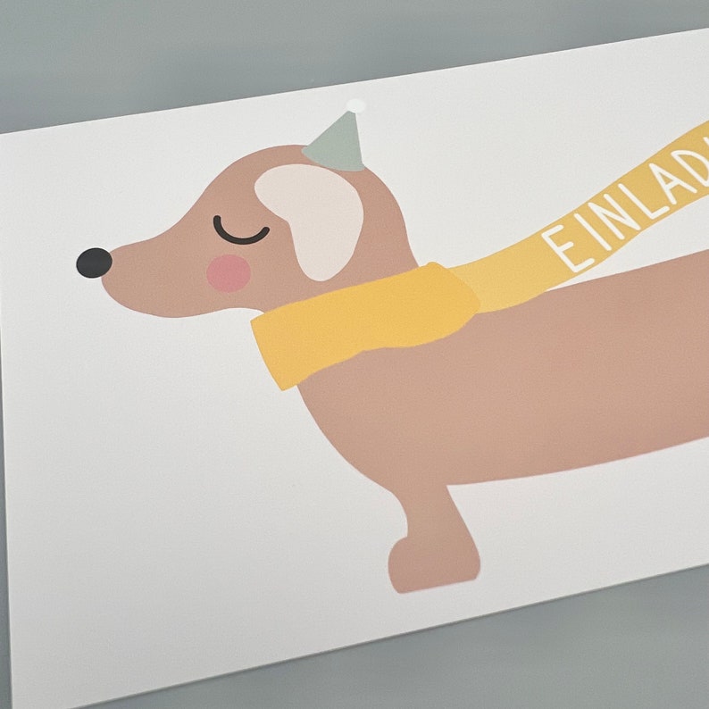 Puede incluir: Un dachshund marr&oacute;n con una bufanda amarilla y un gorro de fiesta con la palabra "EINLAD" en una pancarta amarilla.