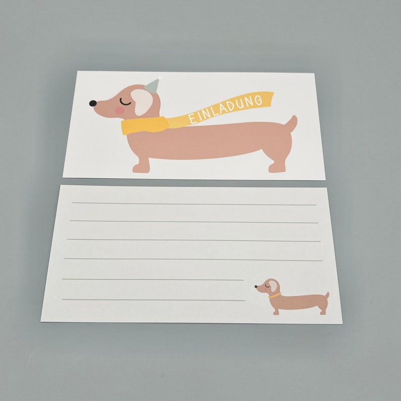Puede incluir: Una tarjeta blanca en blanco con un dachshund que lleva una bufanda amarilla y un gorro de fiesta. La tarjeta dice "Einladung", que en alem&aacute;n significa "Invitaci&oacute;n".