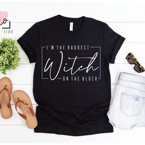 May include: Black t-shirt with white text that reads "I'm the baddest Witch - on the block".