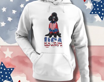 Könnte beinhalten: Weißer Kapuzenpullover mit einem schwarzen Pudel, der eine rot-weiß-blaue Jacke trägt. Das Wort "USA" ist in einer patriotischen Schriftart auf die Vorderseite gedruckt. Der Hintergrund hat einen Aquarell-Effekt mit Sternen.