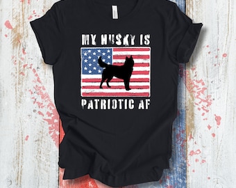 Könnte beinhalten: Schwarzes T-Shirt mit einem Husky-Hund-Silhouette vor einer amerikanischen Flagge. Der Text "MY HUSKY IS PATRIOTIC AF" ist in Weiß über und unter der Flagge gedruckt, für ein patriotisches Design.