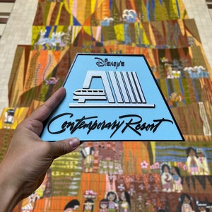 May include: A blue and silver sign with the text "Disney's Contemporary Resort" and a stylised image of the monorail.