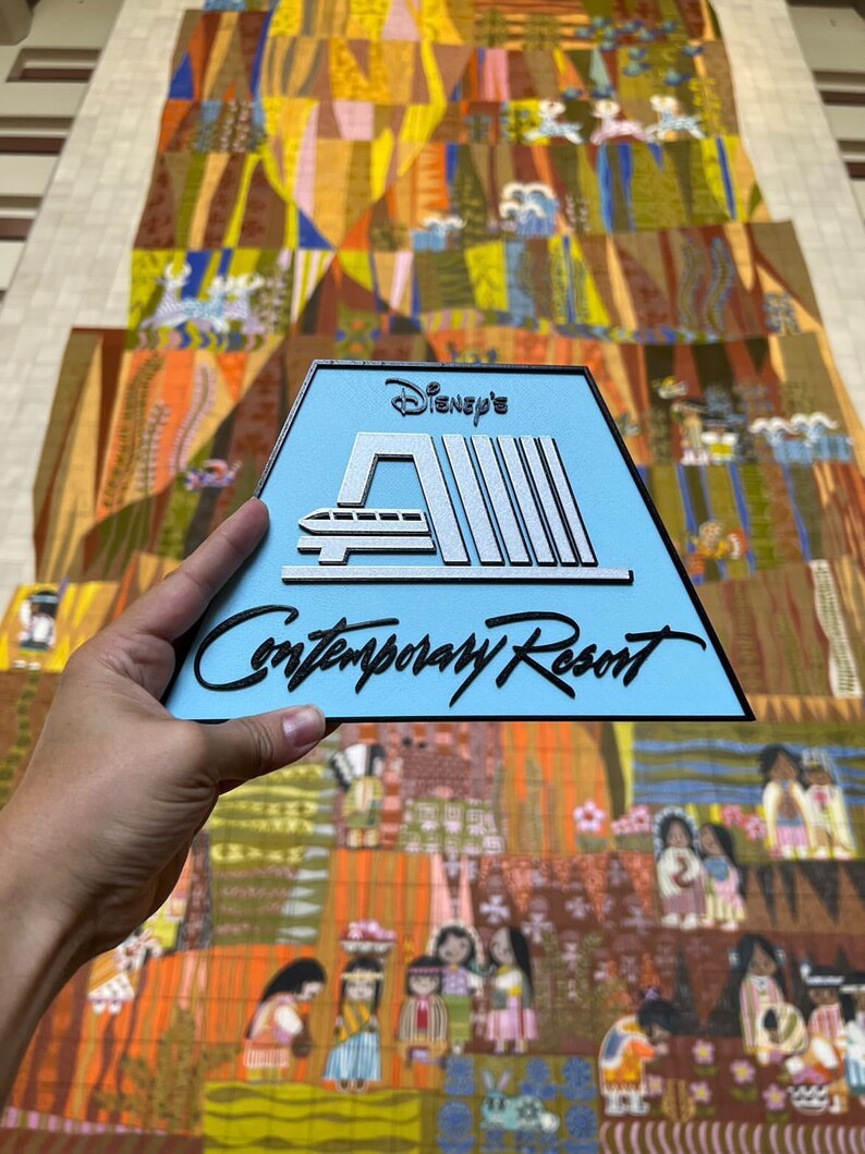 May include: A blue and silver sign with the text "Disney's Contemporary Resort" and a stylised image of the monorail.