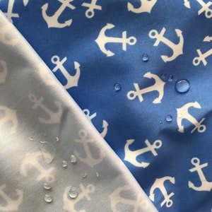 May include: Two pieces of fabric with a white anchor pattern on a blue background. The fabric on the bottom is a lighter blue and has water droplets on it.