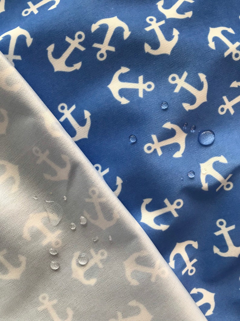 May include: Two pieces of fabric with a white anchor pattern on a blue background. The fabric on the bottom is a lighter blue and has water droplets on it.