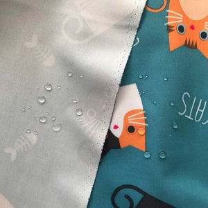 May include: A close-up of a teal fabric with a white, orange, and black cat print. The fabric is waterproof and has water droplets on it. The text "Cats" is visible in the background.