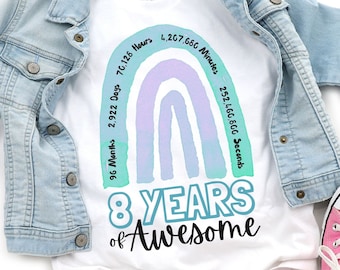 May include: White t-shirt with a rainbow design and the text "8 YEARS of Awesome". The rainbow has numbers around it that represent the time in months, days, hours, minutes, and seconds in 8 years.