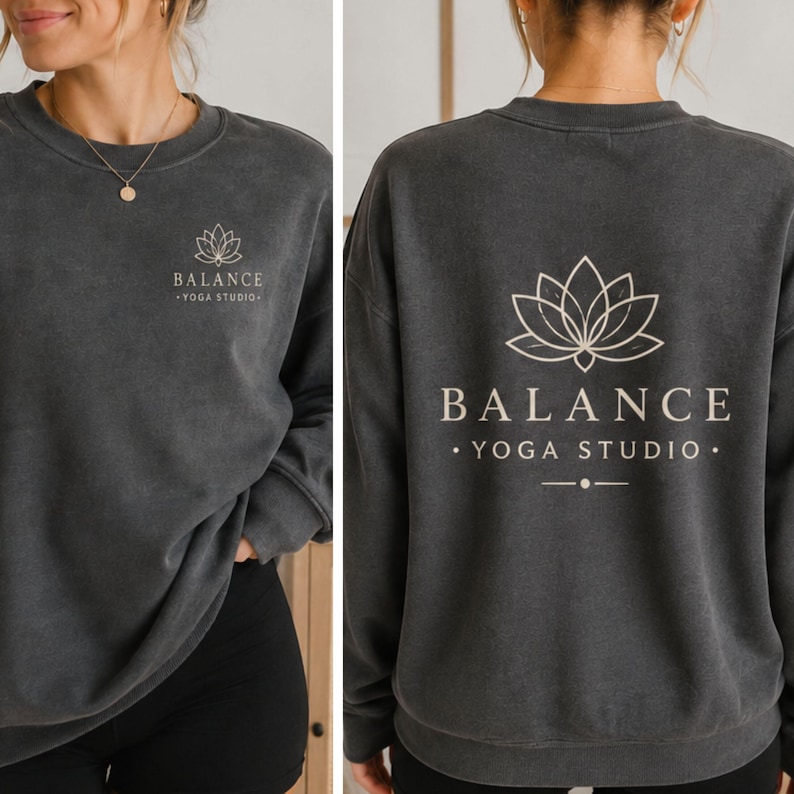 May include: A charcoal gray crewneck sweatshirt featuring a small white lotus flower graphic and the text BALANCE YOGA STUDIO on the left chest, with a larger version of the same lotus graphic and text printed on the back of the garment.