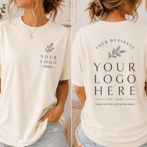 May include: An off-white short-sleeve t-shirt featuring a small black botanical graphic and the text "YOUR LOGO HERE" on the front left chest, and a larger version of the same graphic and text on the back with "EST. 2024" and "THANK YOU FOR SUPPORTING SMALL".