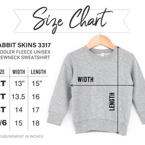 May include: A grey toddler fleece crewneck sweatshirt hanging on a wooden hanger. A size chart displays the Rabbit Skins 3317 model with width and length measurements in inches for sizes 2T, 3T, 4T, and 5/6, ranging from 13 to 15 inches wide and 15 to 18 inches long.