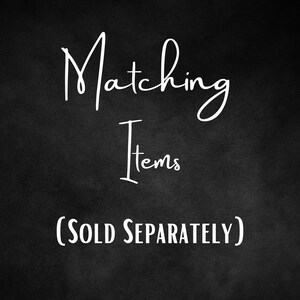 May include: White text on a black background reads "Matching Items" in a cursive font, with "Items" in a simple font. Below, in a simple font, it says "(SOLD SEPARATELY)".