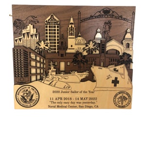 May include: A wooden plaque with a laser-cut design of the San Diego skyline, a ship, and palm trees. The plaque is a 2020 Junior Sailor of the Year award from the Naval Medical Center, San Diego, CA. The text on the plaque reads "2020 Junior Sailor of the Year", "11 APR 2018 - 14 MAY 2022", "The only easy day was yesterday.", and "Naval Medical Center, San Diego, CA".