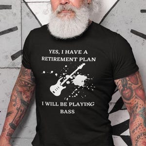 A man with a long white beard wearing a black t-shirt with a humorous text and graphic design.