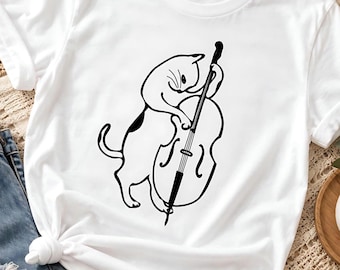 May include: A white short-sleeved t-shirt featuring a black line art graphic of a cat standing on its hind legs and playing a large upright string instrument, such as a double bass or cello, with its paws positioned on the strings.
