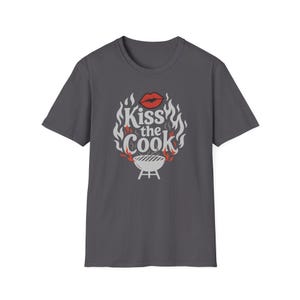 A gray t-shirt with a graphic design featuring a pair of lips and flames surrounding the text "Kiss the Cook".
