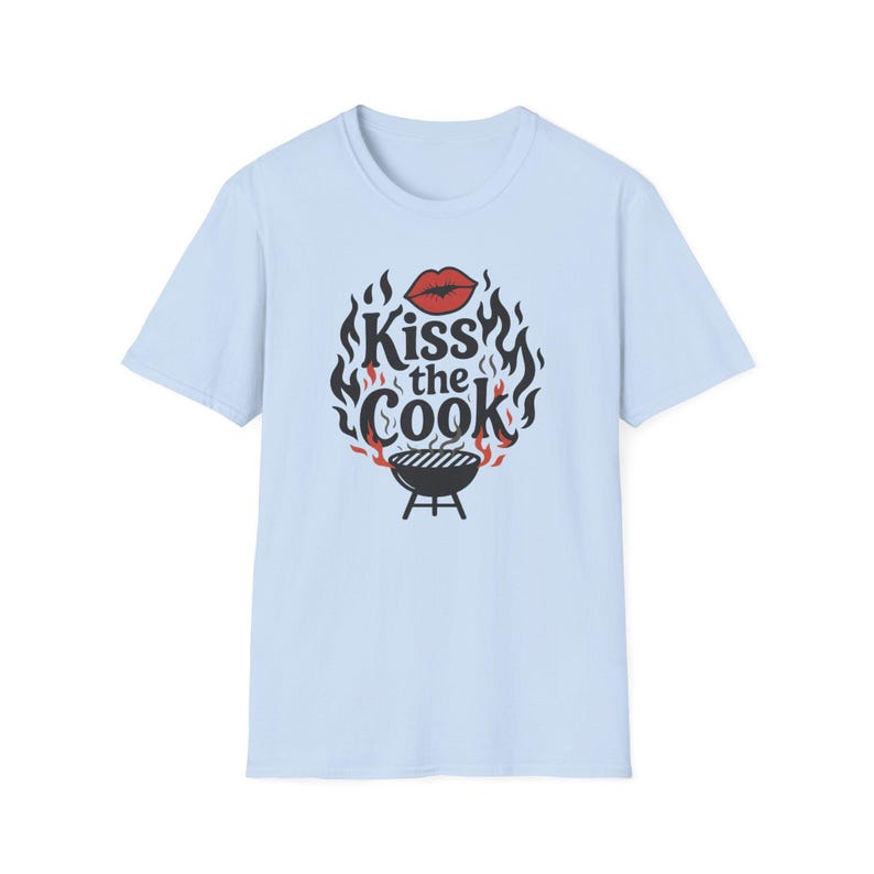 A light blue t-shirt with a graphic design featuring a pair of lips and flames surrounding the text "Kiss the Cook".